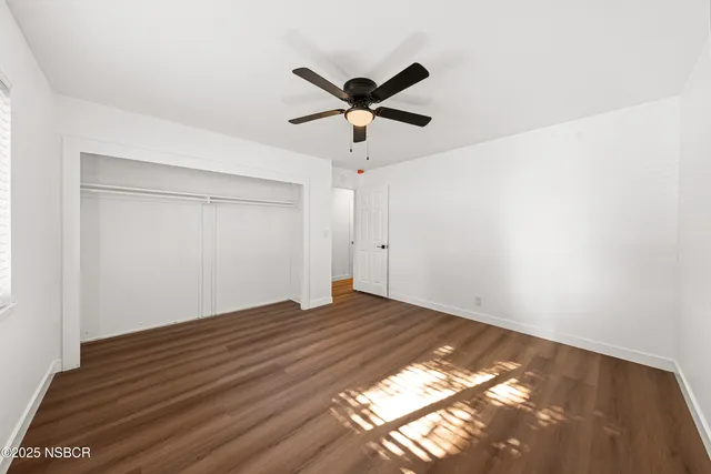 a view of a big room with wooden floor and windows