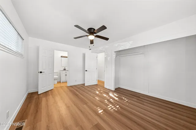 a view of a room with wooden floor and a ceiling fan