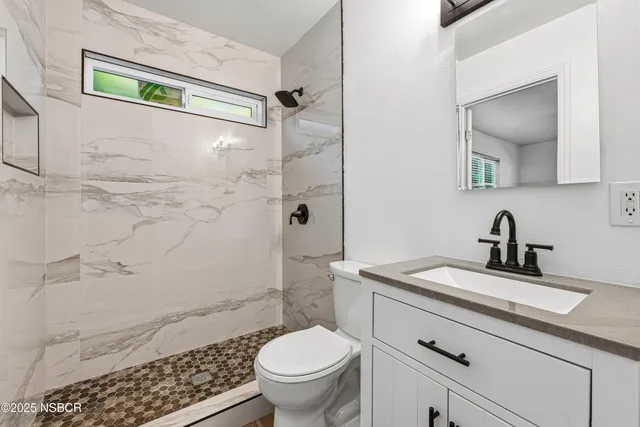 a bathroom with a granite countertop sink toilet and shower