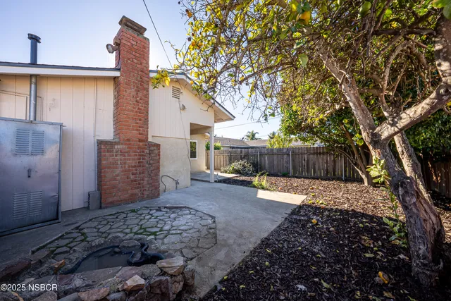 a view of a backyard with large tree and wooden fence