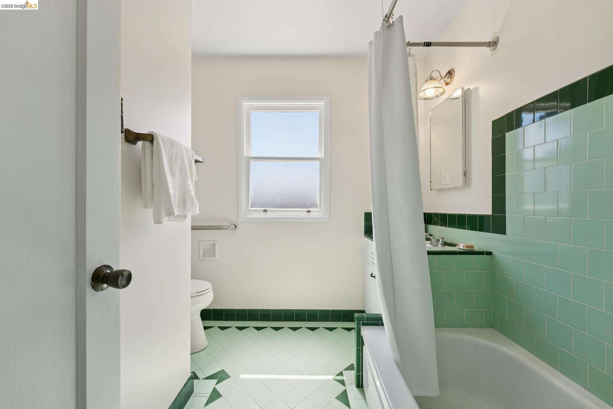 15162 Inverness Street San Leandro, CA 94579 - Photo 15 of 25 Bathroom featuring light green and dark green tile work, a window, and a built-in bathtub