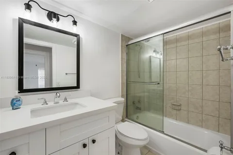 a bathroom with a shower sink vanity mirror and toilet