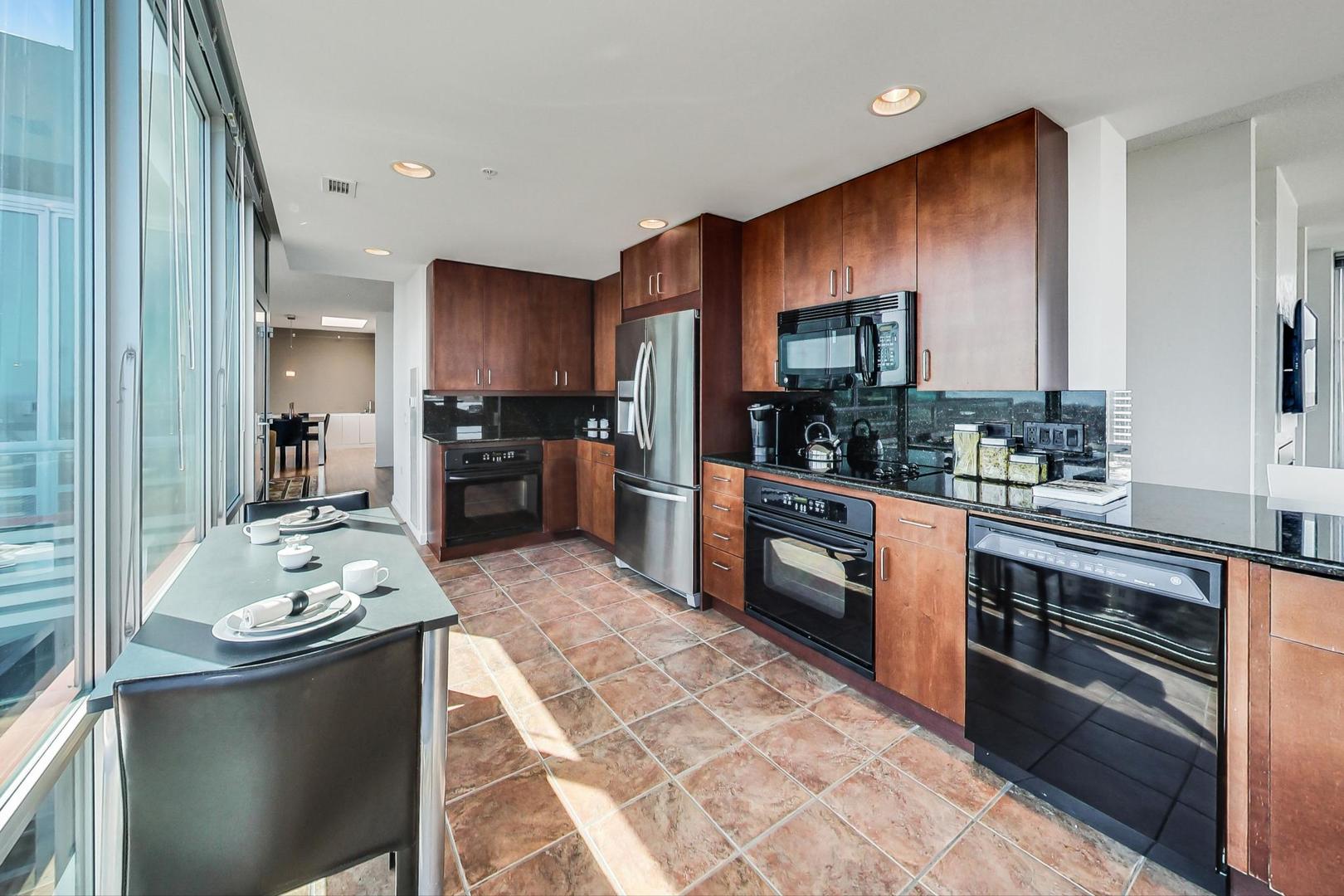 800 Elgin Road, Unit PH02 Evanston, IL 60201 - Photo 12 of 43 a kitchen with stainless steel appliances kitchen island granite countertop a sink dishwasher stove and refrigerator with wooden cabinets