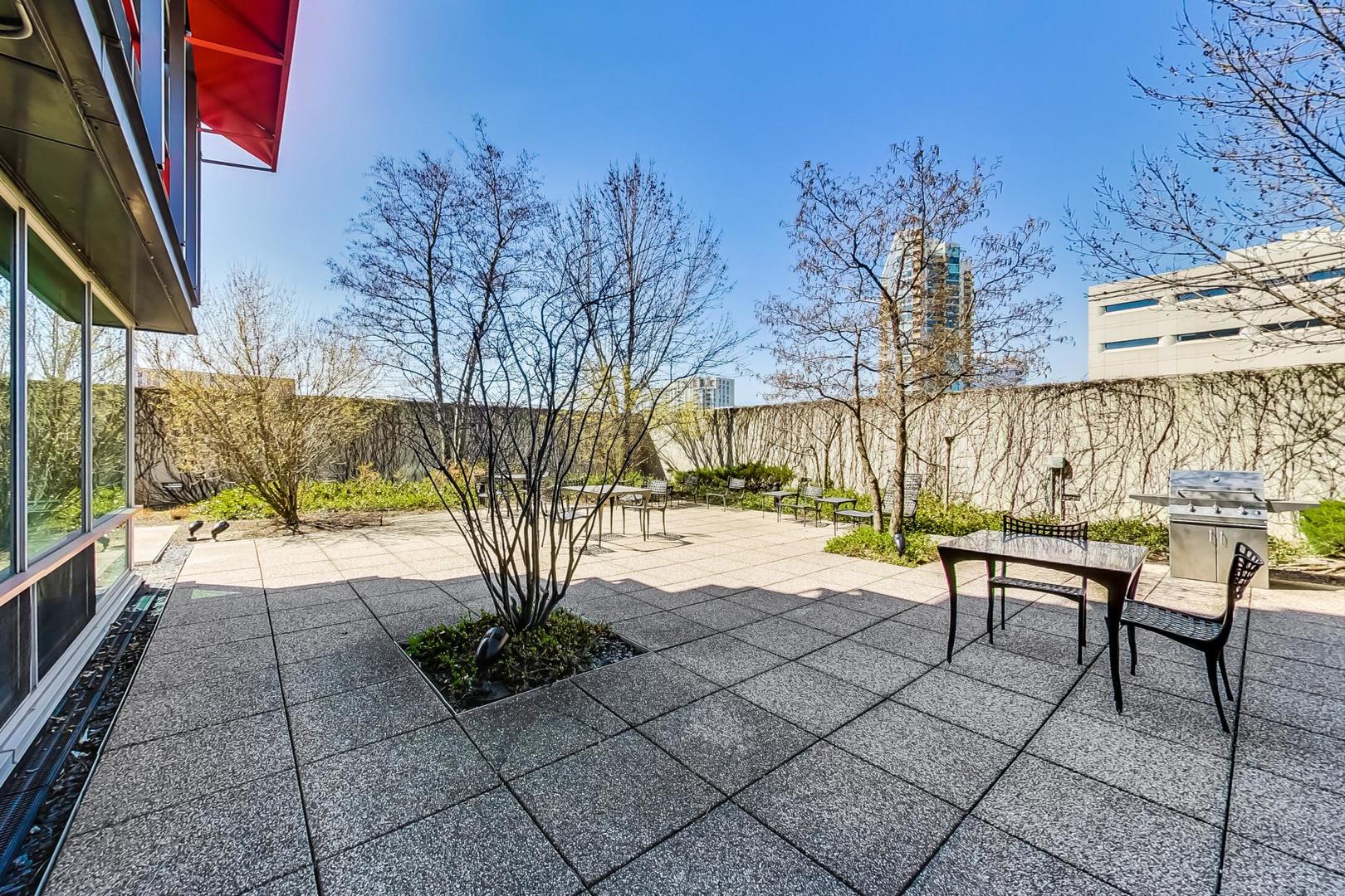 800 Elgin Road, Unit PH02 Evanston, IL 60201 - Photo 39 of 43 a view of a patio with couches and table and chairs next to yard with wooden floor