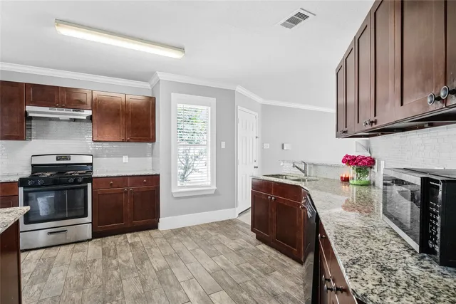 a kitchen with granite countertop a sink stainless steel appliances and cabinets