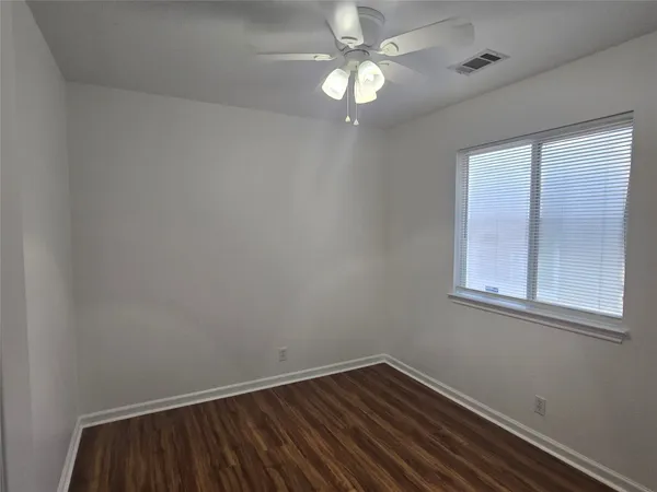 an empty room with a window and ceiling fan