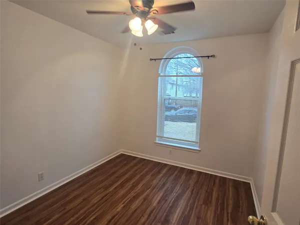 an empty room with wooden floor chandelier fan and windows