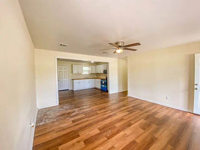 a large kitchen with kitchen island granite countertop wooden floors and white stainless steel appliances