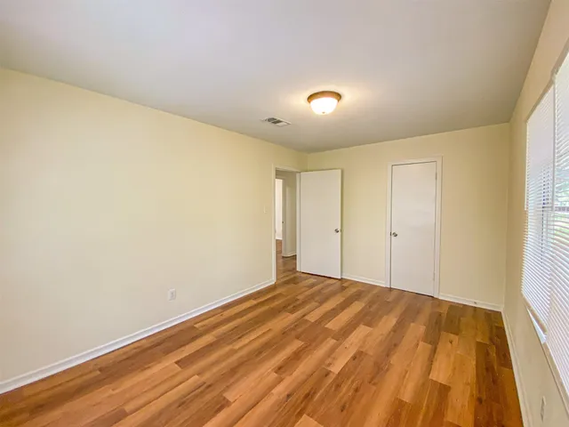 an empty room with wooden floor and windows