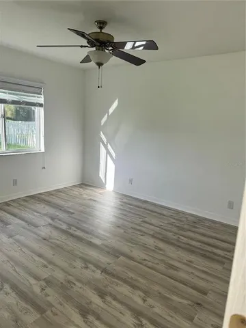 a view of empty room with wooden floor and fan