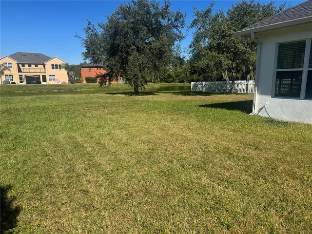 a view of a green field with house in the background