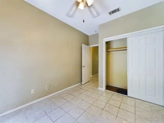 an empty room with closet and a chandelier fan