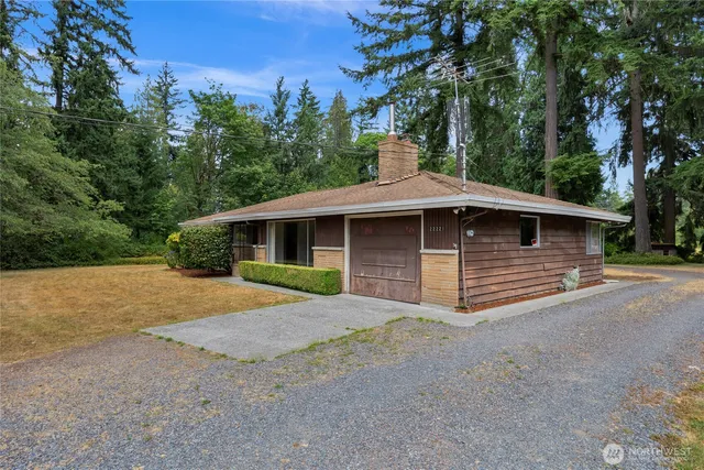 a front view of a house with a garden and trees