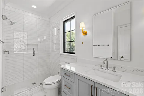 a bathroom with a granite countertop sink toilet and mirror
