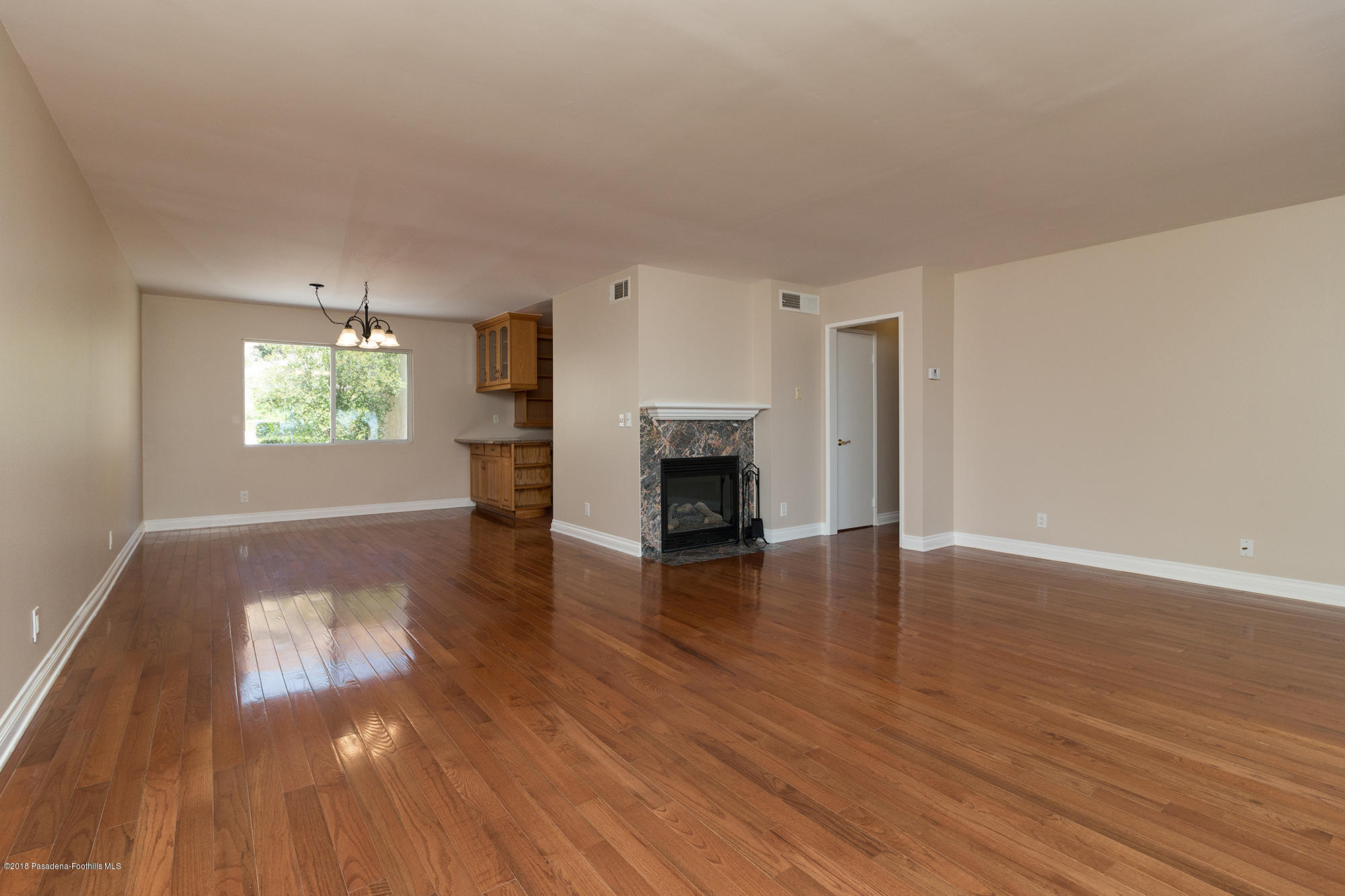 9730 Vía Roma Burbank, CA 91504 - Photo 4 of 24 an empty room with wooden floor and fireplace