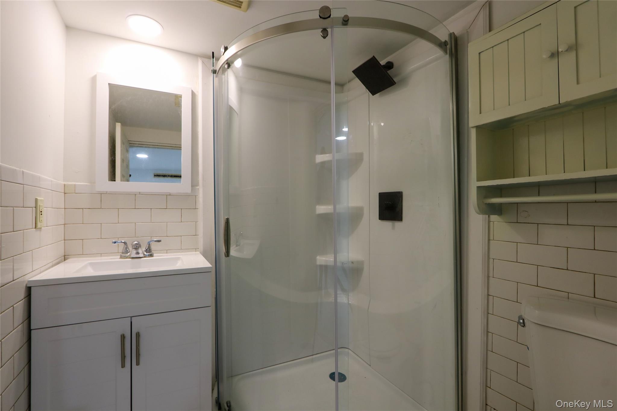 130-55 222nd Street Queens, NY 11413 - Photo 11 of 14 Full bathroom with tile walls, a shower stall, vanity, and tasteful backsplash