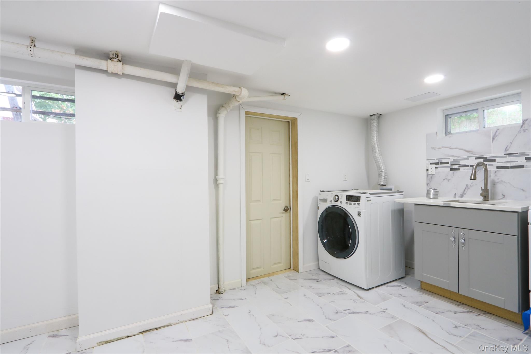 130-55 222nd Street Queens, NY 11413 - Photo 10 of 14 Washroom featuring light marble finish floors, washer / dryer, and cabinet space