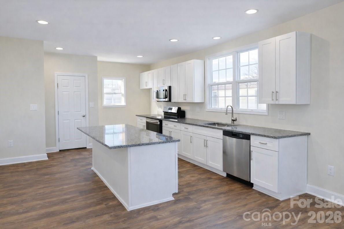 1022 Heath Helms Road Monroe, NC 28110 - Photo 3 of 10 a kitchen with stainless steel appliances granite countertop a sink a stove a refrigerator and white cabinets with wooden floor