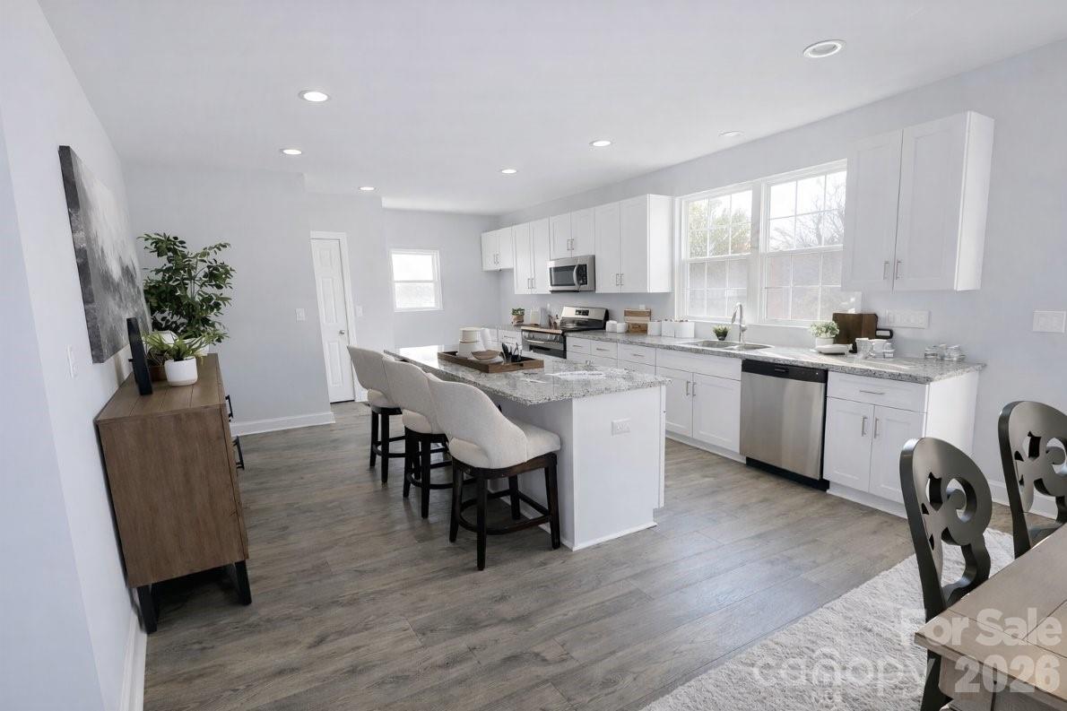 1022 Heath Helms Road Monroe, NC 28110 - Photo 7 of 10 a open dining room with stainless steel appliances kitchen island granite countertop a sink a stove a dining table and chairs