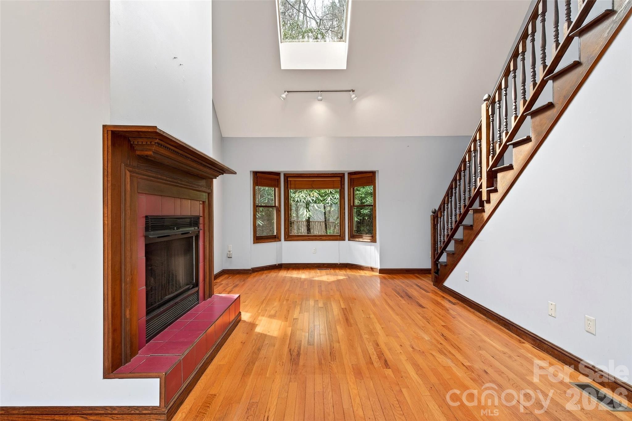 169 Hilltop Road Black Mountain, NC 28711 - Photo 10 of 48 a view of an empty room with wooden floor fireplace and a window