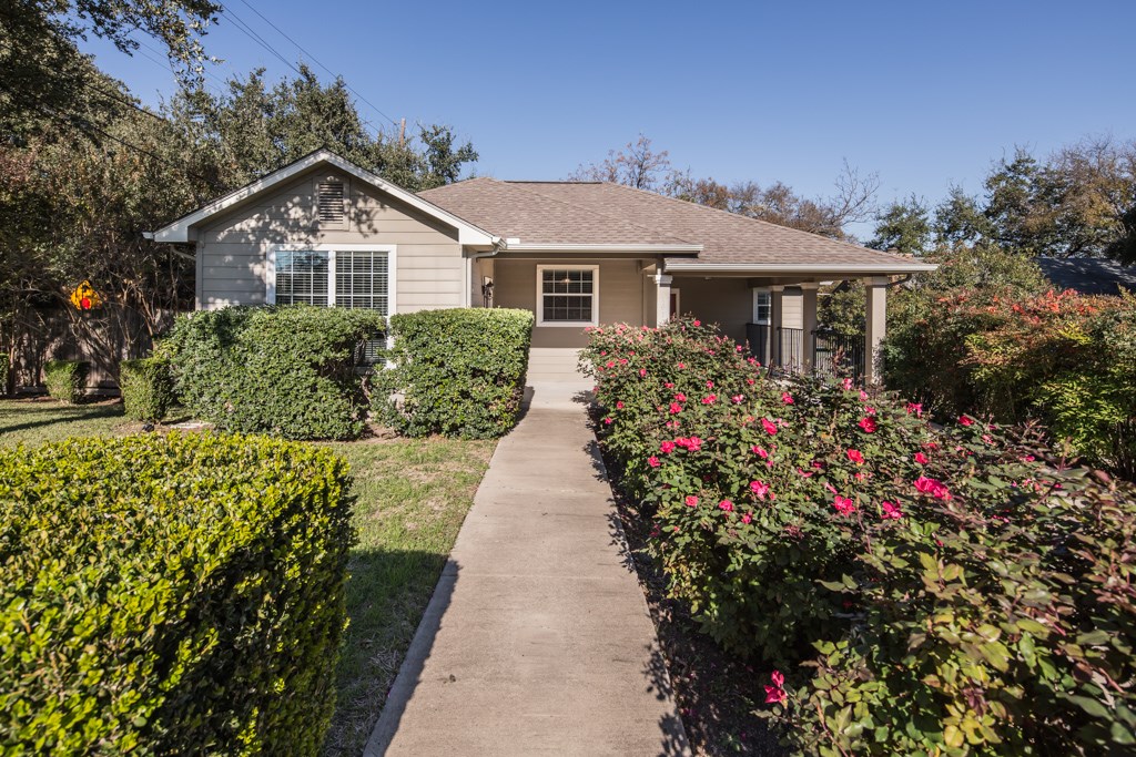 a front view of a house with a yard and potted plants