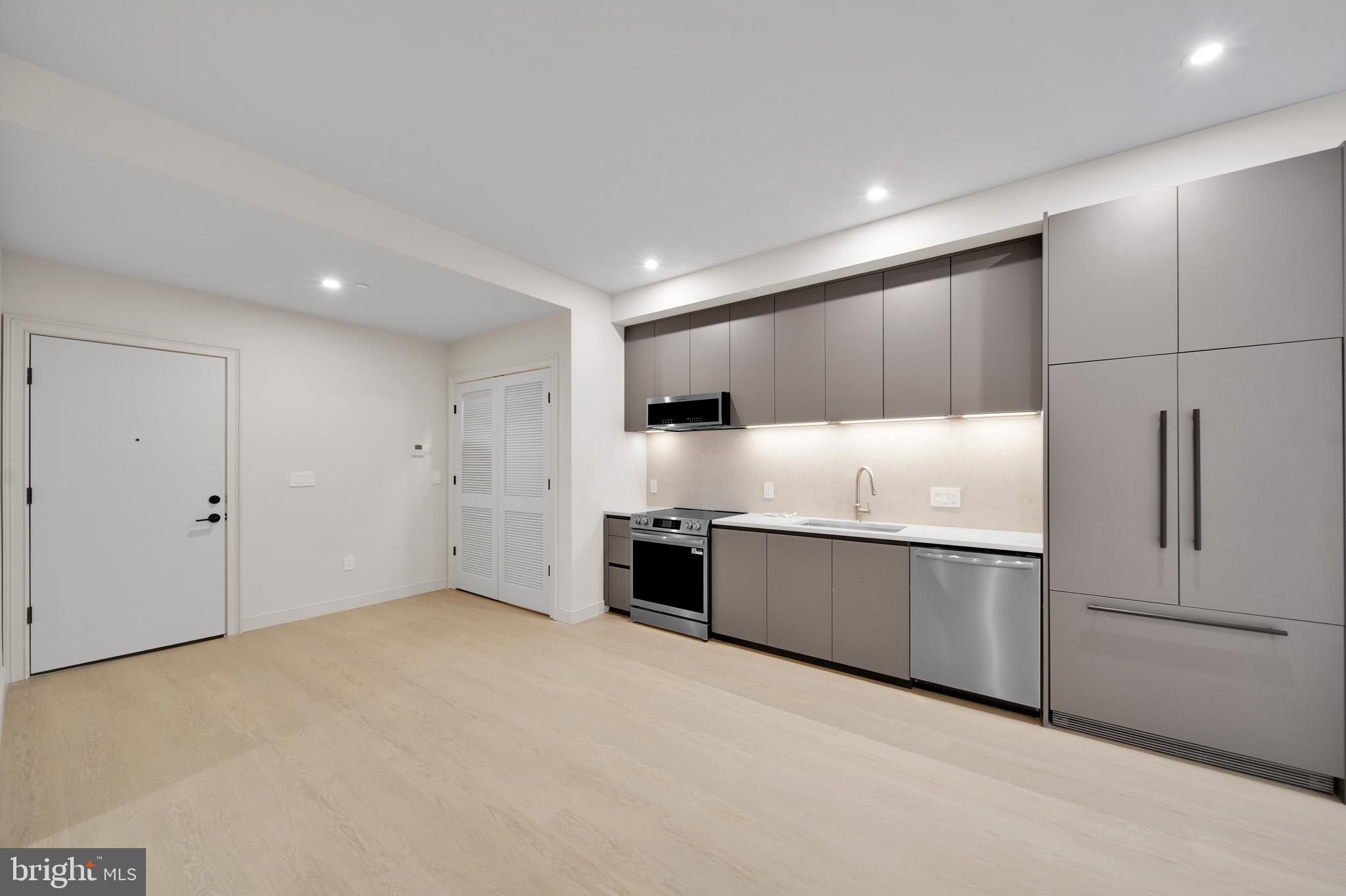 2121 Ward Place Northwest, Unit 405 Washington, DC 20037 - Photo 5 of 18 a large kitchen with stainless steel appliances granite countertop a refrigerator and a sink