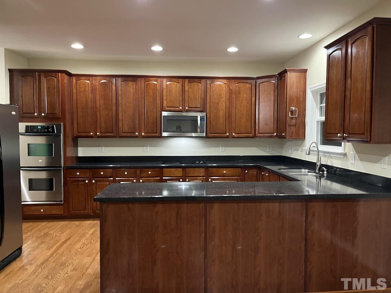 2 Greenway Circle Durham, NC 27705 - Photo 5 of 27 a kitchen with granite countertop wooden cabinets a sink and a stove