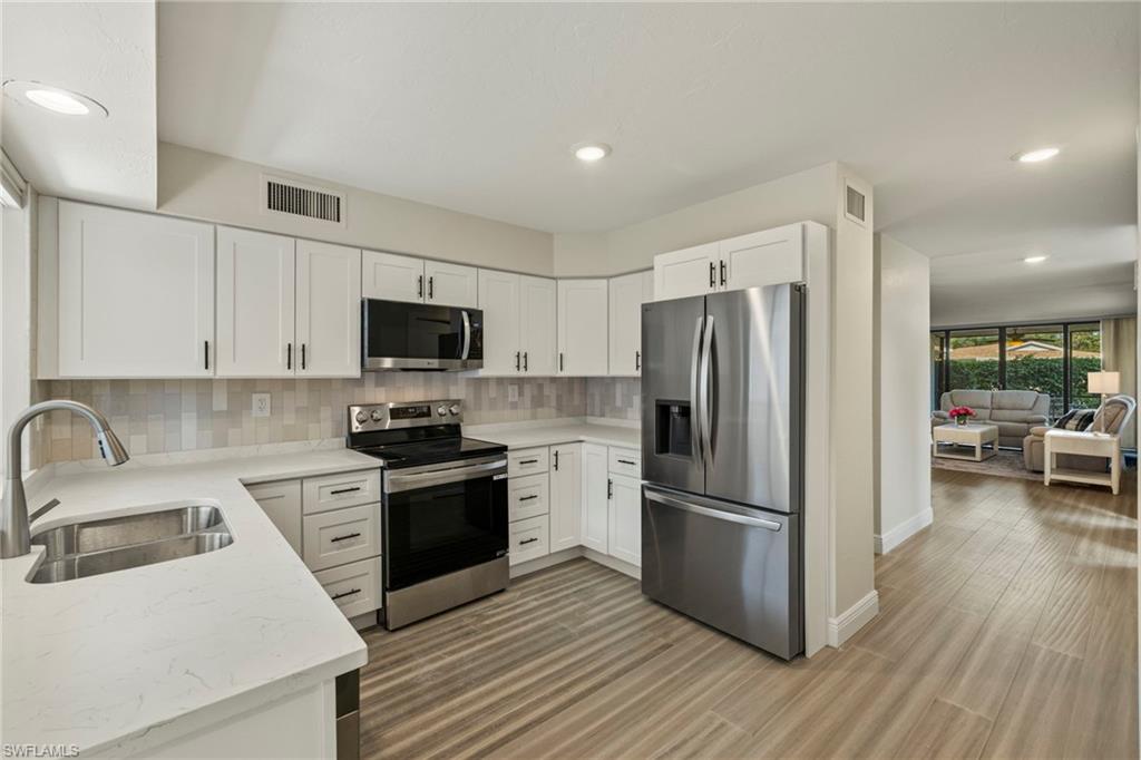 3101 Riviera Drive Naples, FL 34103 - Photo 8 of 41 a kitchen with a refrigerator sink and wooden floor
