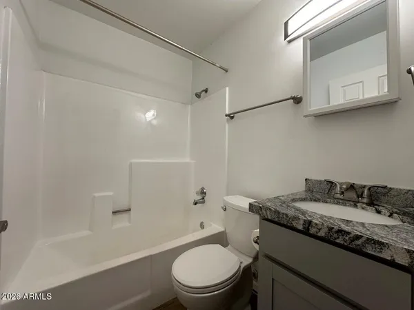 a bathroom with a granite countertop sink a toilet and shower