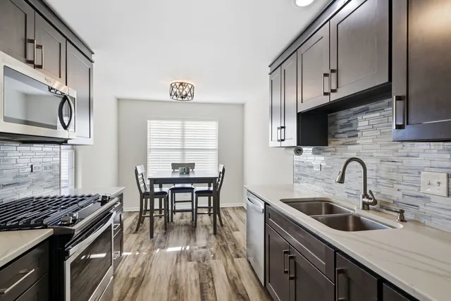 a kitchen with stainless steel appliances a kitchen island hardwood floor sink stove dining table and chairs