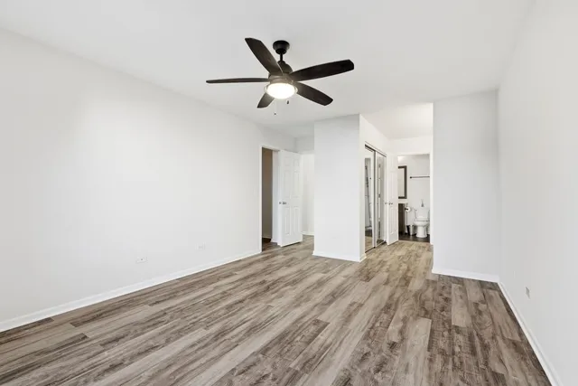 a view of empty room with wooden floor and ceiling fan