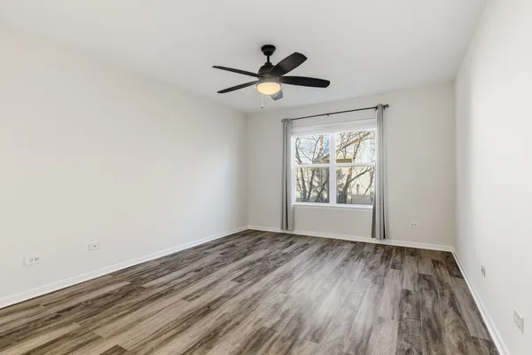 a view of empty room with wooden floor and fan