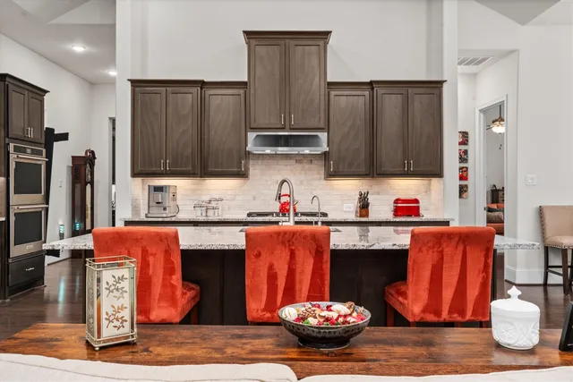 a kitchen with granite countertop a dining table chairs sink and cabinets