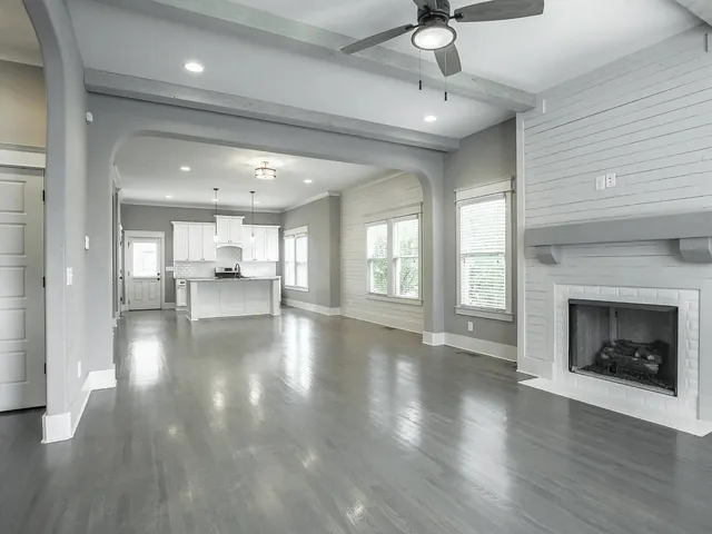 a view of an empty room with kitchen and fireplace