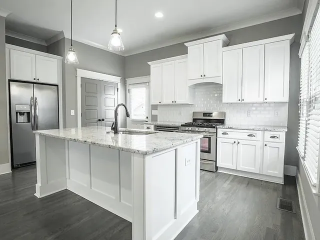a kitchen with kitchen island granite countertop a sink cabinets and stainless steel appliances