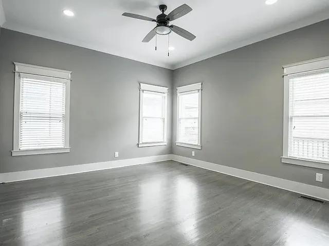 an empty room with wooden floor and windows