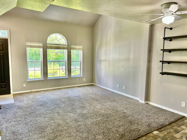 672 West 720 South Logan, UT 84321 - Photo 2 of 15 Spacious room featuring vaulted ceilings, a dark wood-finish entry door, and three windows with an arched transom