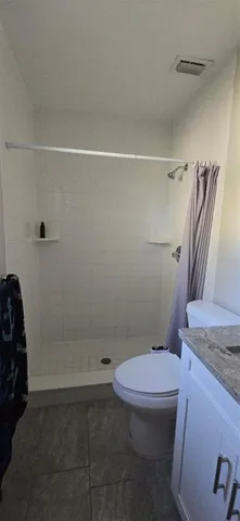 a bathroom with a granite countertop toilet and a shower