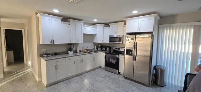 a kitchen with stainless steel appliances granite countertop a refrigerator a stove a sink and a microwave