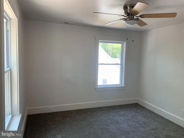an empty room with a window and a fan