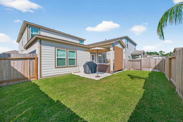 a view of a backyard with table and chairs a barbeque and wooden fence