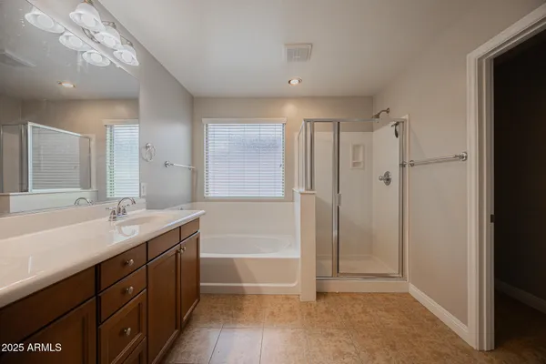 a bathroom with a tub sink shower and two mirror