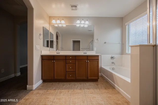 a bathroom with a tub a double vanity sink and a mirror