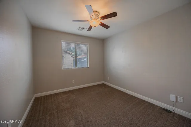 an empty room with a window and a fan