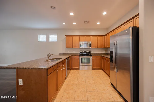 a kitchen with kitchen island granite countertop a sink a counter top space stainless steel appliances and cabinets