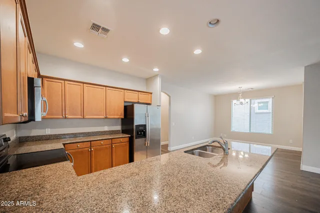 a kitchen with stainless steel appliances granite countertop a sink a stove and a refrigerator