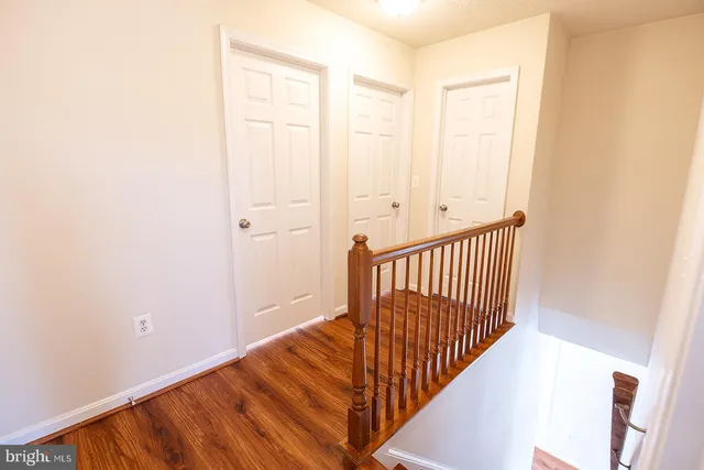 a view of a hallway with wooden floor and a bathroom