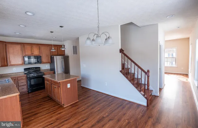 a kitchen with stainless steel appliances granite countertop a refrigerator a stove top oven a sink dishwasher and wooden floor