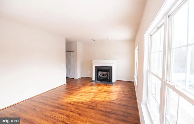 a view of a livingroom with wooden floor a fireplace and windows