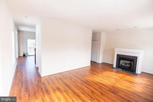 a view of empty room with wooden floor and fireplace